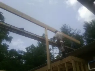 Carpenter setting a ridge beam over a new addition frame — Ice Dam Removal by Roofing Brothers in New Hill