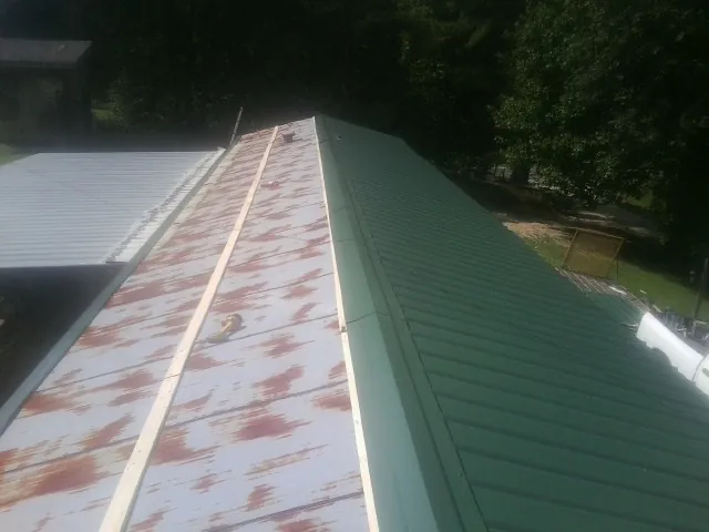 Old rusted panels beside newly installed green metal roofing — Wind Damage Roof Repair by Roofing Brothers in New Hill
