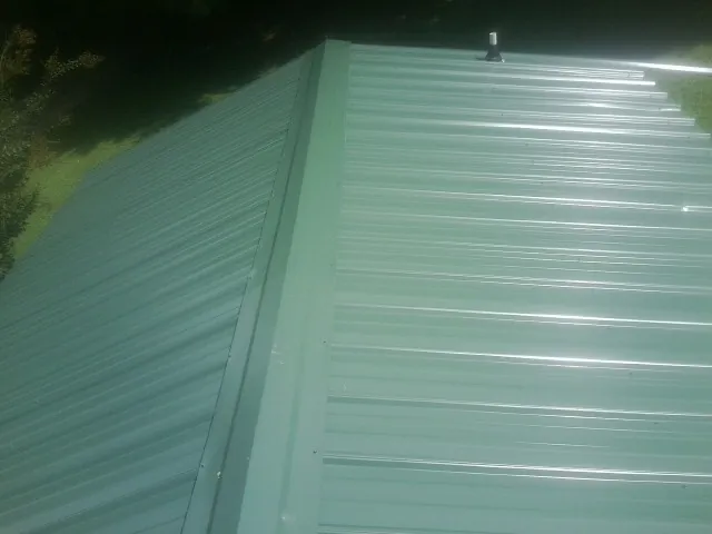 New green metal panels meeting at the ridge of a roof — Flat Roof Repair work by our crew in New Hill