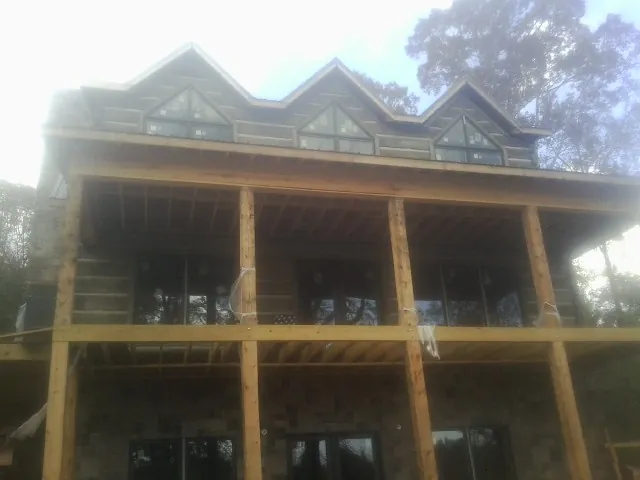 Dormers and porch framing on a large log home under construction — Roof Coating work by our crew in New Hill