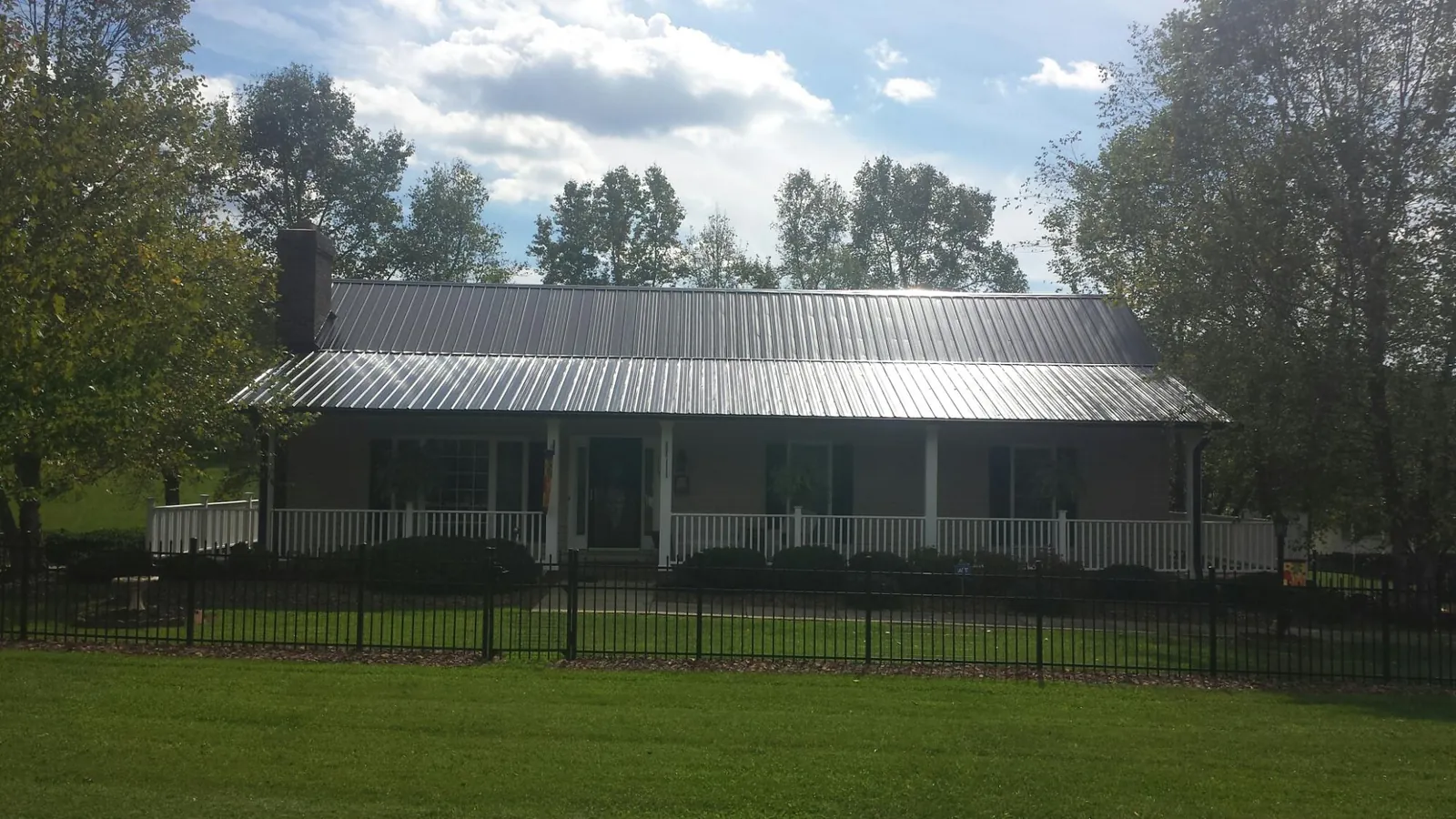 Gray metal roof on a brick ranch with a full width front porch — Gutter Guard Installation work by our crew in New Hill