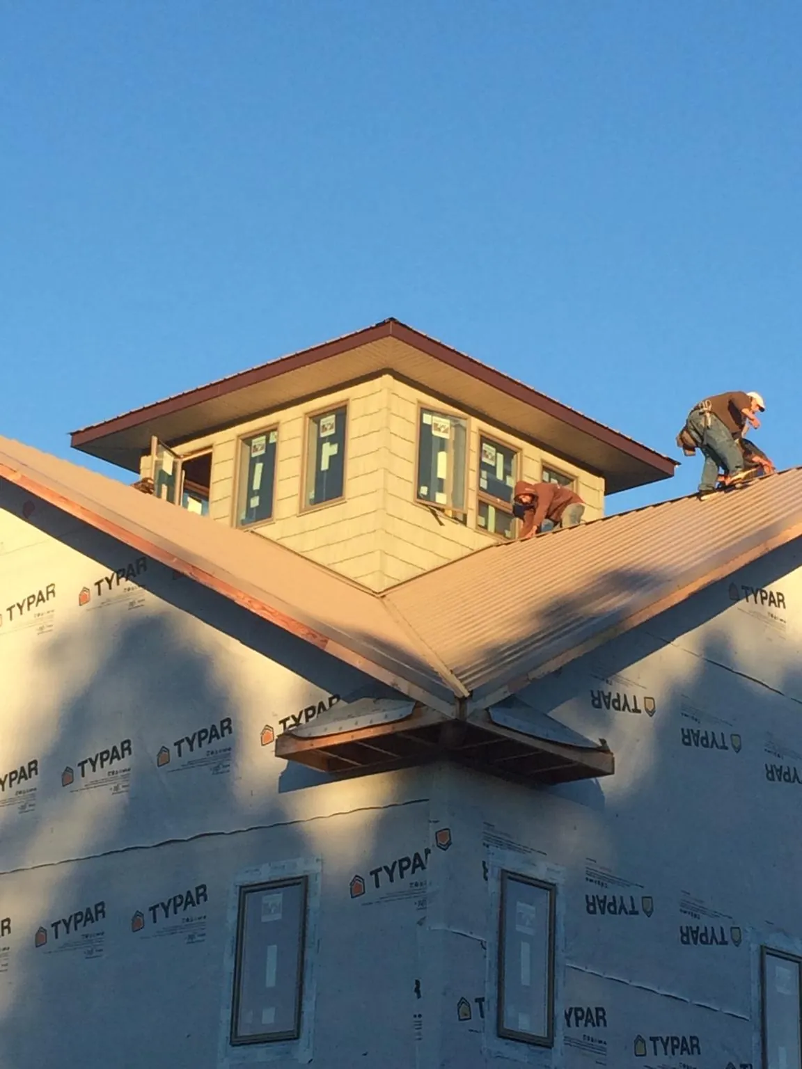 Roofers working around a rooftop cupola on a new metal roof at sunset — Roof Waterproofing in New Hill by Roofing Brothers